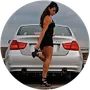 A woman in a black dress is standing in front of a white car.